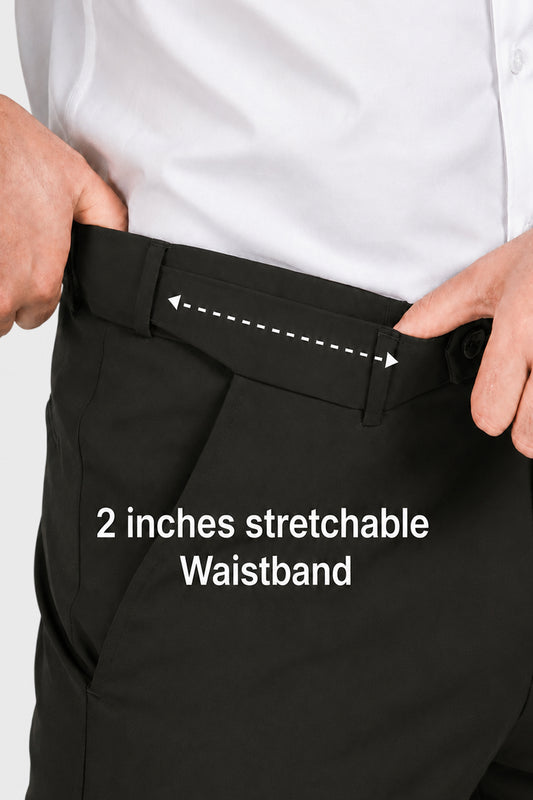 Close-up of a person wearing black trousers and a white shirt, demonstrating a stretchable waistband with hands pulling the front panel outward. White text reads '2 inches stretchable Waistband' with a dashed arrow indicating the stretch area.