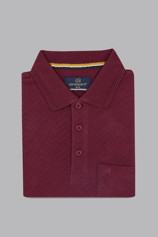 Folded maroon polo shirt with brand label on a gray background